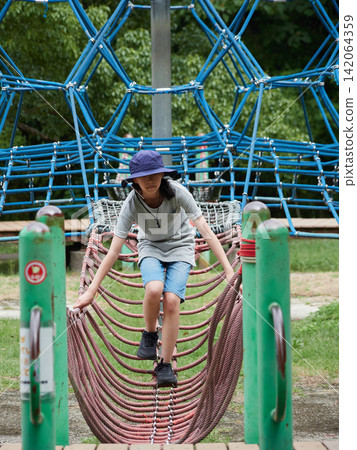 一群可愛的孩子在盛夏的公園玩繩索攀爬遊戲。 一群可愛的孩子在盛夏的公園玩繩索攀爬遊戲。 142064359