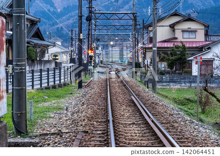 A local Japanese railway and tracks running through a residential area nestled in the mountains. A local Japanese railway and tracks running through a residential area nestled in the mountains. 142064451