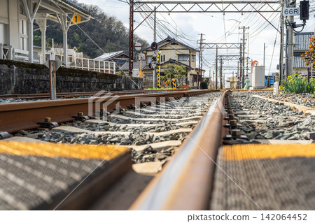 A low-angle view of a local Japanese train station, showing the tracks and platform. A low-angle view of a local Japanese train station, showing the tracks and platform. 142064452