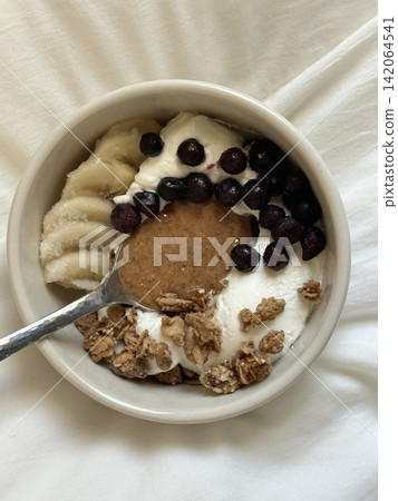 Creamy yogurt bowl topped with fresh fruits and crunchy toppings, offering a smooth texture and refreshing taste. Light, wholesome, and visually appealing, perfect for breakfast or healthy snack. 142064541
