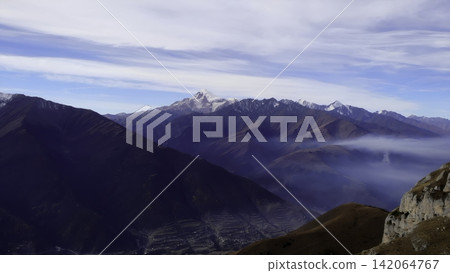 Snowy alpine peaks above a misty mountain valley Snowy alpine peaks above a misty mountain valley 142064767