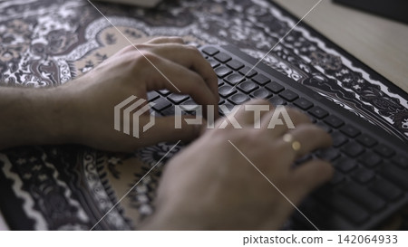 Person Swiftly Inputting Data On Keyboard. Rapid Keystrokes Executed On Patterned Mouse Pad Workspace. Media Person Swiftly Inputting Data On Keyboard. Rapid Keystrokes Executed On Patterned Mouse Pad Workspace. Media 142064933