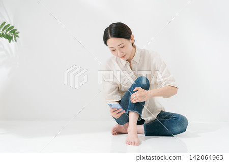 Full-body portrait of a woman looking at her smartphone Full-body portrait of a woman looking at her smartphone 142064963