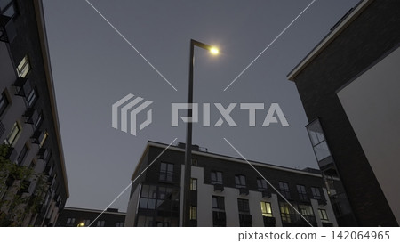 Evening City Illumination. City Street Softly Illuminated By Lampposts During Peaceful Night Hours. Stock Clip Evening City Illumination. City Street Softly Illuminated By Lampposts During Peaceful Night Hours. Stock Clip 142064965