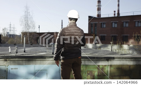Worker in hard hat standing on industrial rooftop Worker in hard hat standing on industrial rooftop 142064966