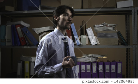 Businessman holding a marker in a dim archive room Businessman holding a marker in a dim archive room 142064985