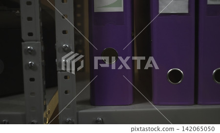 Purple ring binders on a metal office shelf Purple ring binders on a metal office shelf 142065050