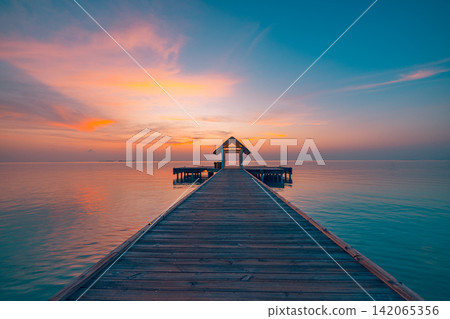 Breathtaking wooden jetty stretching over calm azure lagoon glowing pastel dusk Maldives resort. Luxury travel honeymoon paradise scenic. Exotic getaway wallpaper decor Breathtaking wooden jetty stretching over calm azure lagoon glowing pastel dusk Maldives resort. Luxury travel honeymoon paradise scenic. Exotic getaway wallpaper decor 142065356