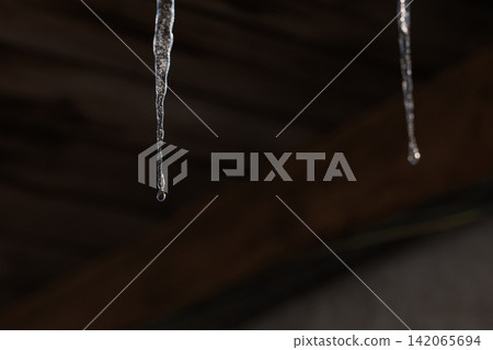 Melting icicles and falling water drops: Close-up of spring thaw on blurred wooden background Melting icicles and falling water drops: Close-up of spring thaw on blurred wooden background 142065694