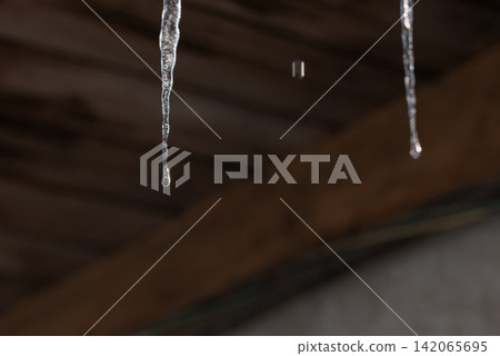 Melting icicles and falling water drops: Close-up of spring thaw on blurred wooden background Melting icicles and falling water drops: Close-up of spring thaw on blurred wooden background 142065695