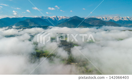 Aerial view of foggy Pyrenees mountains with snow capped peaks above clouds and green forests in Catalonia Spain Aerial view of foggy Pyrenees mountains with snow capped peaks above clouds and green forests in Catalonia Spain 142066403