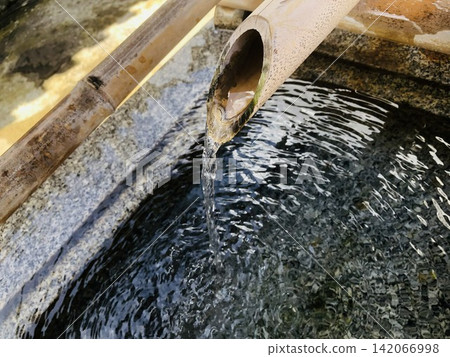 清水從竹製水龍頭流入日式花園的水盆中。 清水從竹製水龍頭流入日式花園的水盆中。 142066998