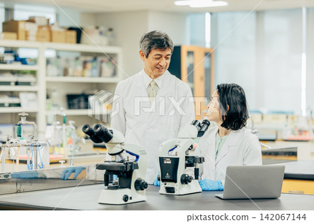 身穿白大褂的男女研究人員在實驗室進行研究。 身穿白大褂的男女研究人員在實驗室進行研究。 142067144