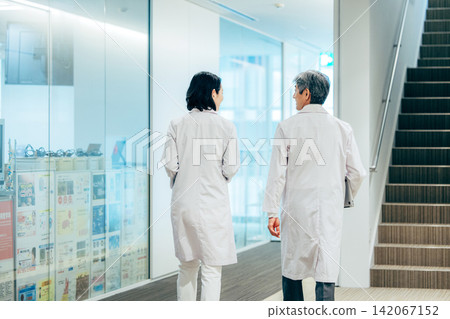 一名男醫生和一名女醫生在醫院走廊交談。 142067152