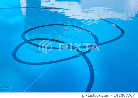 Cleaning of pool. Corrugated hose under blue water Cleaning of pool. Corrugated hose under blue water 142067767