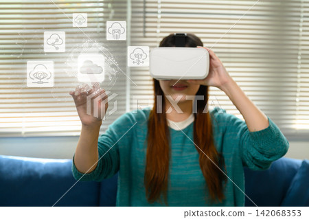 Asian Woman Wearing VR Headset Touching Virtual Cloud Computing Icons in Futuristic Digital Interface Asian Woman Wearing VR Headset Touching Virtual Cloud Computing Icons in Futuristic Digital Interface 142068353