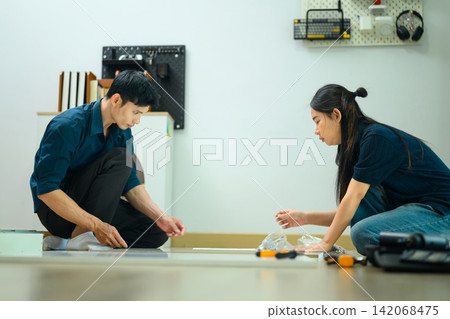 Asian Couple Assembling Flat Pack Furniture Together on Living Room Floor Asian Couple Assembling Flat Pack Furniture Together on Living Room Floor 142068475