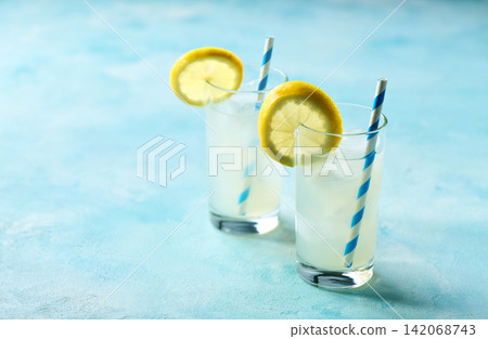 A glass of cold lemonade with fresh lemon slice on the kitchen table. A glass of cold lemonade with fresh lemon slice on the kitchen table. 142068743