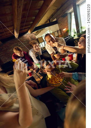 Office team raising drinks and cheering together during informal party Office team raising drinks and cheering together during informal party 142069220