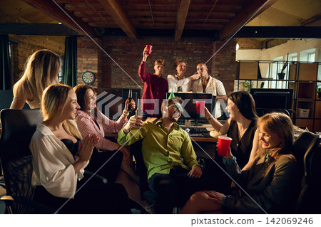 Coworkers sharing drinks and conversation during relaxed office party Coworkers sharing drinks and conversation during relaxed office party 142069246