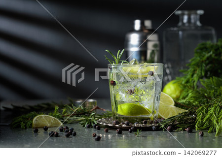 Cocktail Gin and tonic with ice, juniper berries, and a lime wedges. Cocktail Gin and tonic with ice, juniper berries, and a lime wedges. 142069277