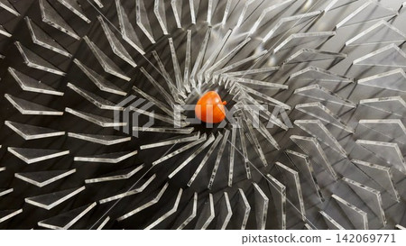 Top view on spiral geometric installation with metallic radial elements surrounding a red apple-shaped object in the center. Strong symmetry, depth and optical movement create a striking visual focus Top view on spiral geometric installation with metallic radial elements surrounding a red apple-shaped object in the center. Strong symmetry, depth and optical movement create a striking visual focus 142069771