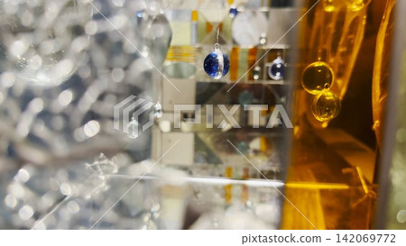 Abstract glass installation with suspended spheres and mirrored surfaces. Light reflections and refractions create layered shapes, depth, and a surreal geometric composition Abstract glass installation with suspended spheres and mirrored surfaces. Light reflections and refractions create layered shapes, depth, and a surreal geometric composition 142069772