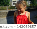 Smiling Girl in Red Dress Outdoors on a Sunny Day 142069857