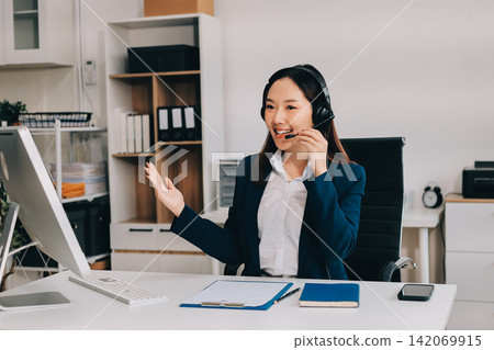 Smiling Asian Woman Telemarketing Agent with Headset Working at Smiling Asian Woman Telemarketing Agent with Headset Working at 142069915