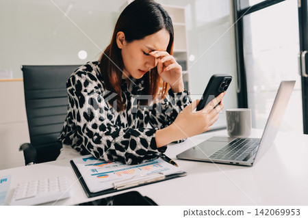 Tried young Asian office employee feeling sick and have a headache from a long working day at office Tried young Asian office employee feeling sick and have a headache from a long working day at office 142069953