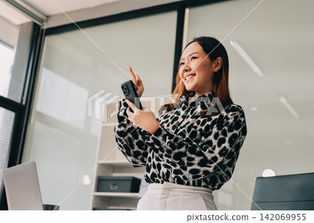 Confident asian business woman standing in modern office Confident asian business woman standing in modern office 142069955