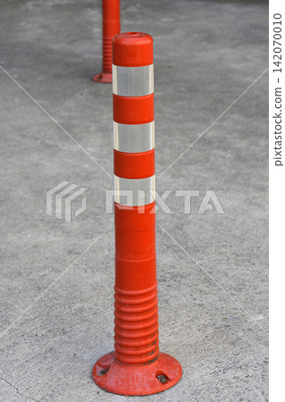 Orange plastic traffic bollard on concrete surface Orange plastic traffic bollard on concrete surface 142070010