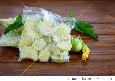 Vacuum packed zucchini slices with fresh vegetables on rustic wooden background Vacuum packed zucchini slices with fresh vegetables on rustic wooden background 142070443