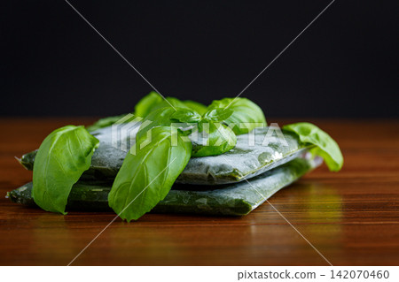Frozen basil portions prepared for storage on brown wooden background Frozen basil portions prepared for storage on brown wooden background 142070460
