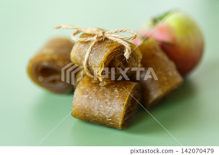 Healthy natural apple snack rolls arranged with fresh fruit on green background 142070479
