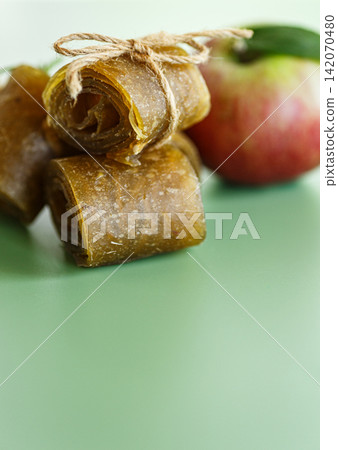Homemade dried apple leather spirals with twine and apple on soft background Homemade dried apple leather spirals with twine and apple on soft background 142070480