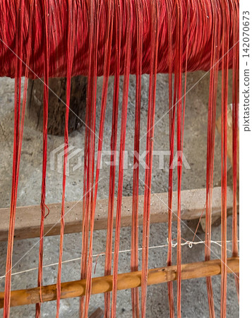 Red Dyed Textile Threads on Traditional Loom Red Dyed Textile Threads on Traditional Loom 142070673