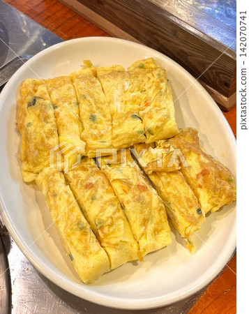 Gyeran-mari or rolled omelette in Korean cuisine is a savory banchan (side dish) made with beaten eggs mixed onion, carrot, Korean zucchini, scallions, and garlic chives. Similiar with tamagoyaki Gyeran-mari or rolled omelette in Korean cuisine is a savory banchan (side dish) made with beaten eggs mixed onion, carrot, Korean zucchini, scallions, and garlic chives. Similiar with tamagoyaki 142070741
