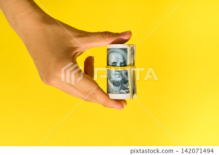 Hand holding roll of hundred dollar bills Hand holding roll of hundred dollar bills 142071494