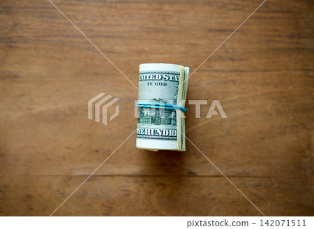 Rolled hundred dollar bills on wooden background 142071511