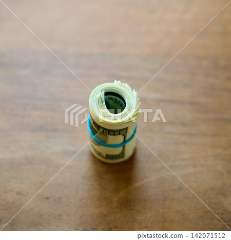 Rolled hundred dollar bills on wooden background Rolled hundred dollar bills on wooden background 142071512