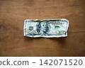 Crumpled one hundred dollar bill on wood background 142071520