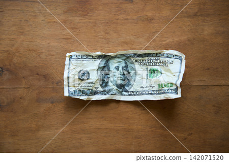 Crumpled one hundred dollar bill on wood background 142071520
