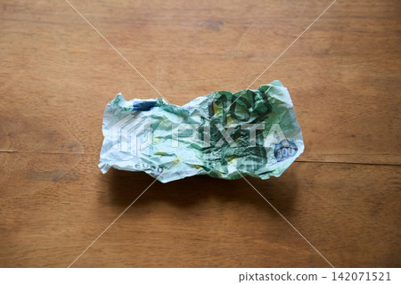 Crumpled hundred euro bill on wood background Crumpled hundred euro bill on wood background 142071521