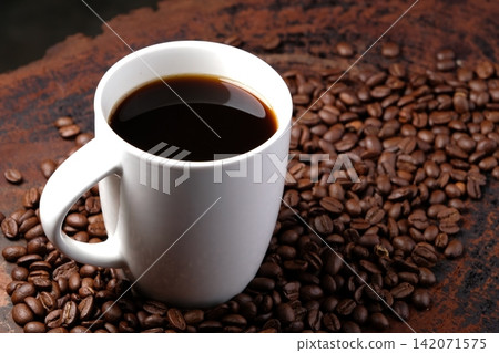 black coffee in white mug with surrounded by roasted coffee beans on dark red wood table black coffee in white mug with surrounded by roasted coffee beans on dark red wood table 142071575