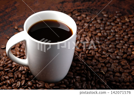 black coffee in white mug with surrounded by roasted coffee beans on dark red wood table black coffee in white mug with surrounded by roasted coffee beans on dark red wood table 142071576