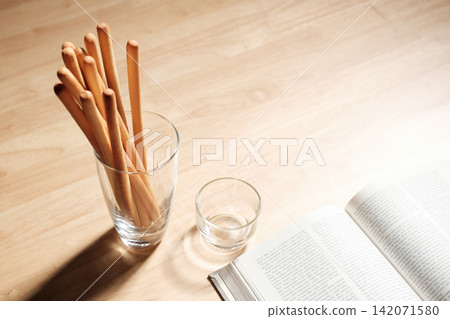 breadsticks in transparent glass with an opened page of a book on wood table breadsticks in transparent glass with an opened page of a book on wood table 142071580