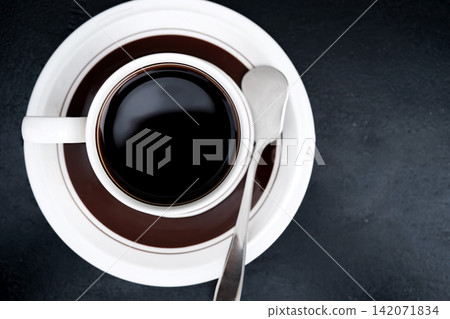 top view of morning hot black coffee cup on dark table with tea spoon top view of morning hot black coffee cup on dark table with tea spoon 142071834