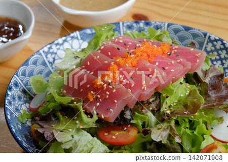 A Japanese tuna sashimi salad in a Japanese-patterned bowl, drizzled with Japanese soy sauce and topped with tobiko. A Japanese tuna sashimi salad in a Japanese-patterned bowl, drizzled with Japanese soy sauce and topped with tobiko. 142071908