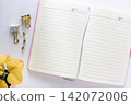 Open pink planner with blank lined pages, gold vintage clips and yellow leaves plant. 142072006